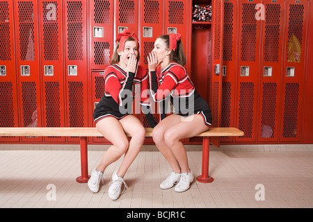 Cheerleaders gossiping in locker room Stock Photo