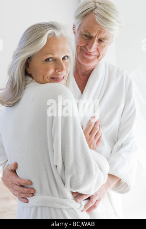 Middle aged couple in bathrobes hugging Stock Photo