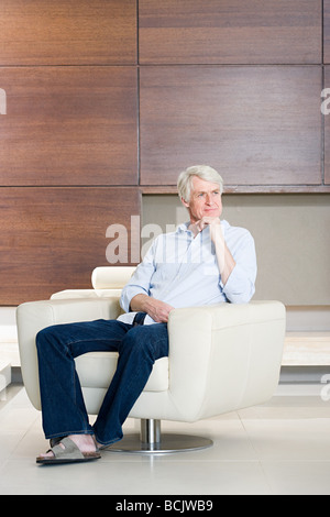 Thoughtful middle aged man sitting on modern armchair Stock Photo