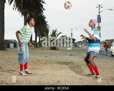 Boys playing football in street Stock Photo