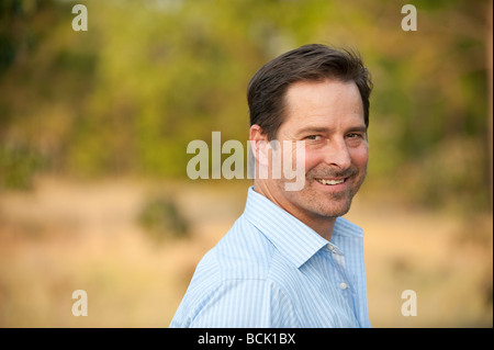 Man in a blue button down shirt looking back smiling Stock Photo