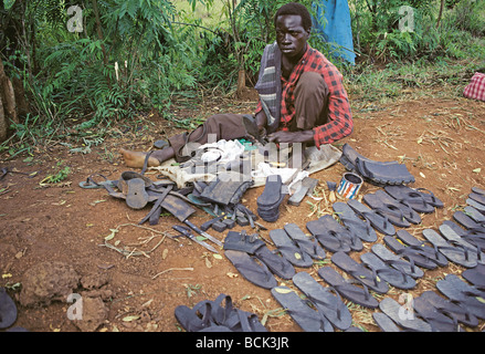 Man making flip flop sandals from rubber tyres for sale at Port Masindi market Uganda East Africa Stock Photo