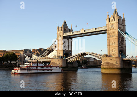 Replica of a 19th century Mississippi paddleboat passing though Tower Bridge London England UK Europe at sundown Stock Photo