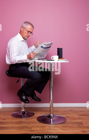 Businessman reading a newspaper sat in a cafe Stock Photo