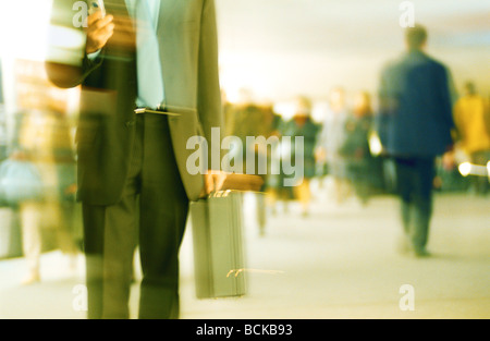 Businessman walking in concourse with crowd in background, blurred motion Stock Photo