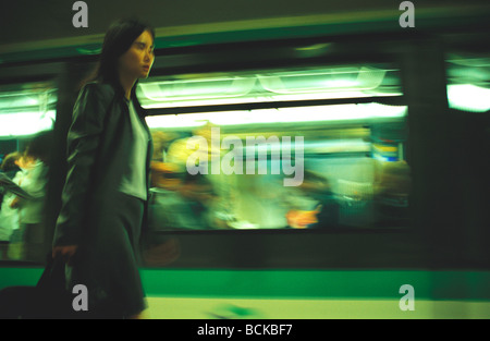 Woman walking on subway platform next to subway train, blurred Stock Photo