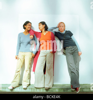 Three young women leaning against wall Stock Photo