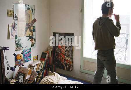 Young man in bedroom, looking out of window, rear view Stock Photo