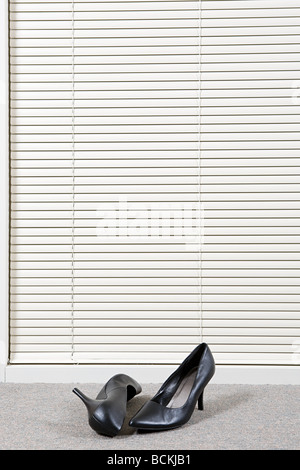 Pair of high heeled shoes in front of venetian blinds Stock Photo