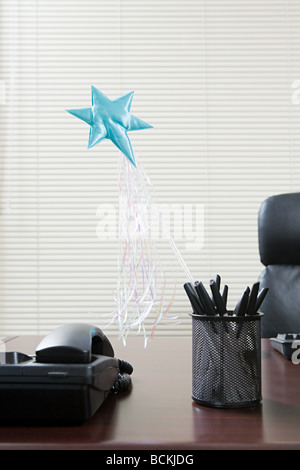 Magic wand sticking out of pen holder on office desk Stock Photo