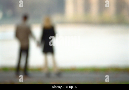 Couple holding hands looking at water, rear view, blurred Stock Photo