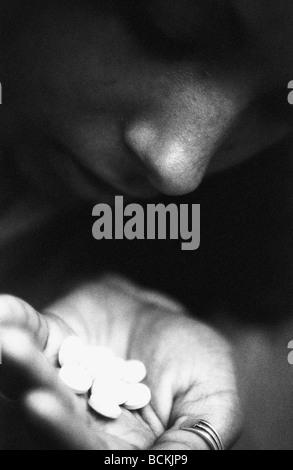 Person looking down at handful of pills, b&w Stock Photo