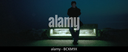 Man sitting on bench in dark, panoramic view Stock Photo