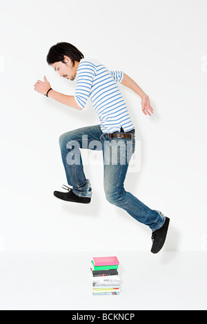 Young man jumping over books Stock Photo