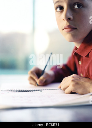 Boy writing at table Stock Photo