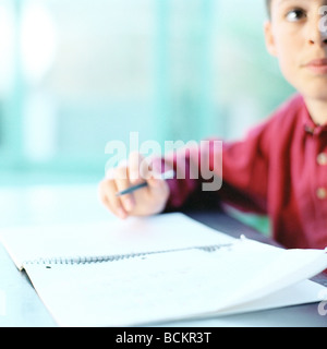 Boy writing at table Stock Photo