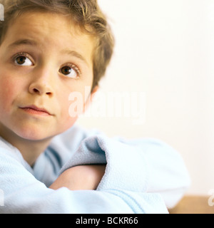 Child with arms crossed looking up Stock Photo