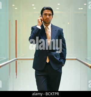 Businessman standing with cellphone in elevator Stock Photo