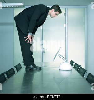 Man standing on table looking down at screen Stock Photo