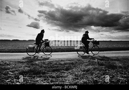 Two people on bicycles on road through fields, b&w Stock Photo