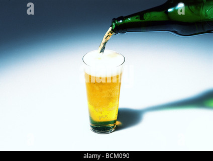 Pouring glass of beer from bottle Stock Photo