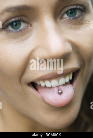 Woman sticking out tongue, showing piercing, looking at camera, close-up Stock Photo