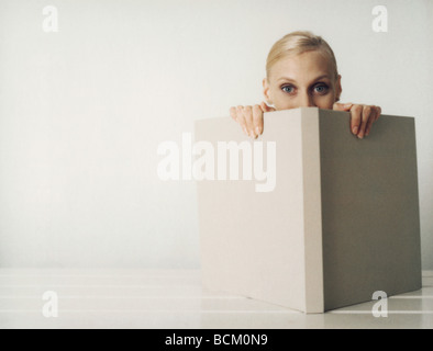 Woman peeking over edge of open book, looking at camera Stock Photo