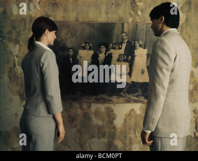 Man and woman standing side by side, looking at black and white photo on wall, rear view Stock Photo