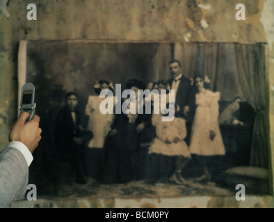 Man using cell phone to photograph black and white family photo on wall, cropped Stock Photo