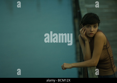 Woman leaning on railing of pier, looking at camera Stock Photo