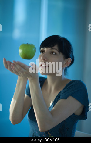 Apple floating in air above woman's hands Stock Photo