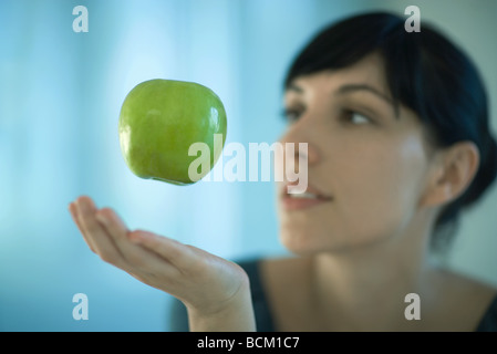 Apple floating in air above woman's hand Stock Photo