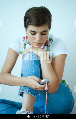 Teenage girl resting head on knee, looking at cell phone Stock Photo