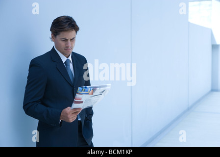 Businessman standing, reading newspaper Stock Photo