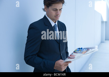 Businessman standing, reading newspaper Stock Photo