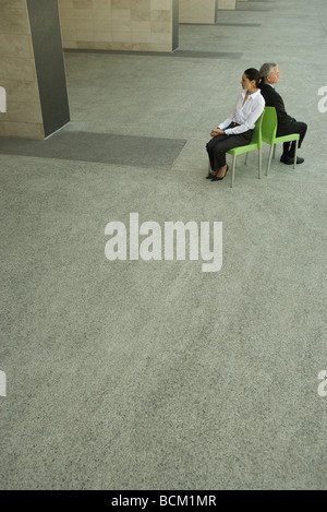 Businesswoman and businessman sitting back to back, high angle view, full length Stock Photo