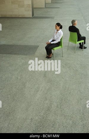 Businesswoman and businessman sitting back to back, high angle view, full length