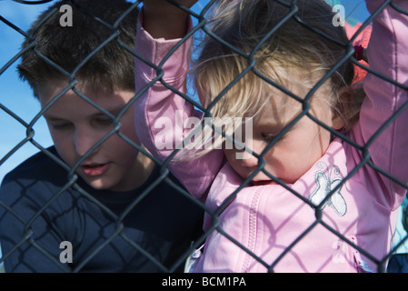 Boy and girl looking through chainlink fence, close-up Stock Photo