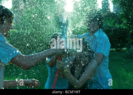 Young friends having water fight with garden hose Stock Photo