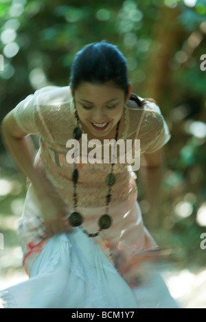 Young woman bending over outdoors, holding up skirt, smiling Stock Photo