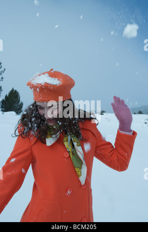 Teenage girl being hit with snowball, looking away, smiling Stock Photo