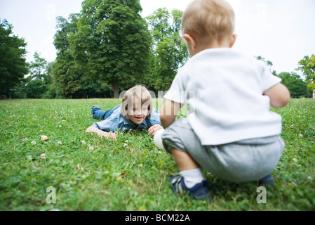 Siblings face to face outdoors, playing with ball, one with Down's Syndrome Stock Photo