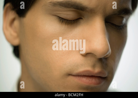 Young man furrowing brow, eyes closed, portrait Stock Photo