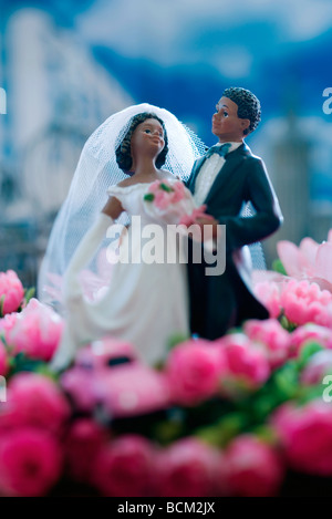 Plastic bride and groom standing in field of fake flowers Stock Photo