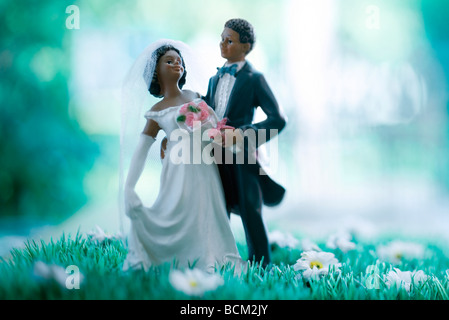 Plastic bride and groom standing in field of fake flowers Stock Photo