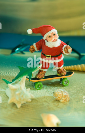 Santa Claus figurine skateboarding on beach Stock Photo