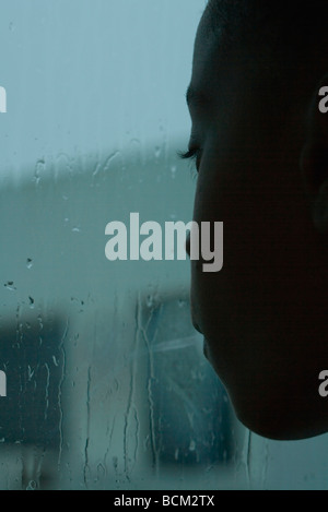 Girl looking out window on rainy day, close-up Stock Photo