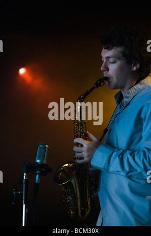 Young man playing saxophone in night club Stock Photo