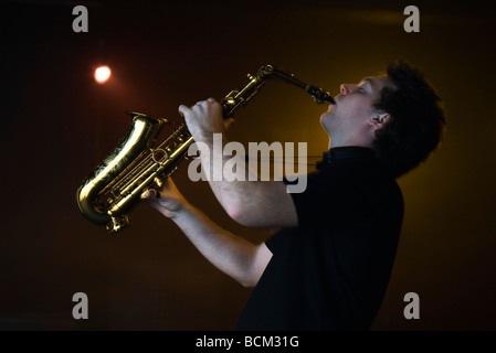 Young man playing saxophone in night club, side view Stock Photo