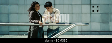 Young couple standing outdoors, reading book together Stock Photo